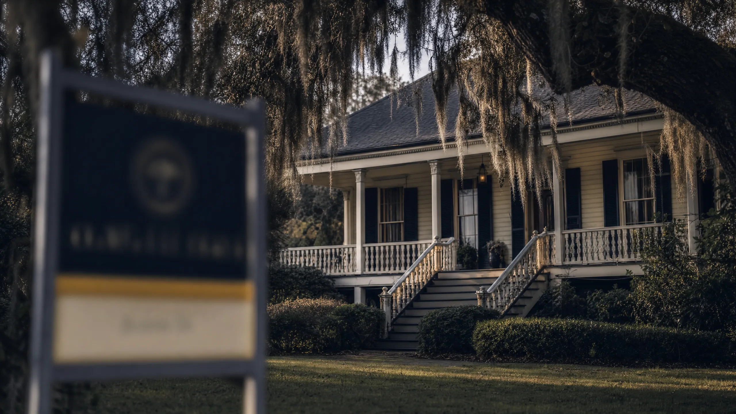 Louisiana home with for-sale sign under live oak with Spanish moss